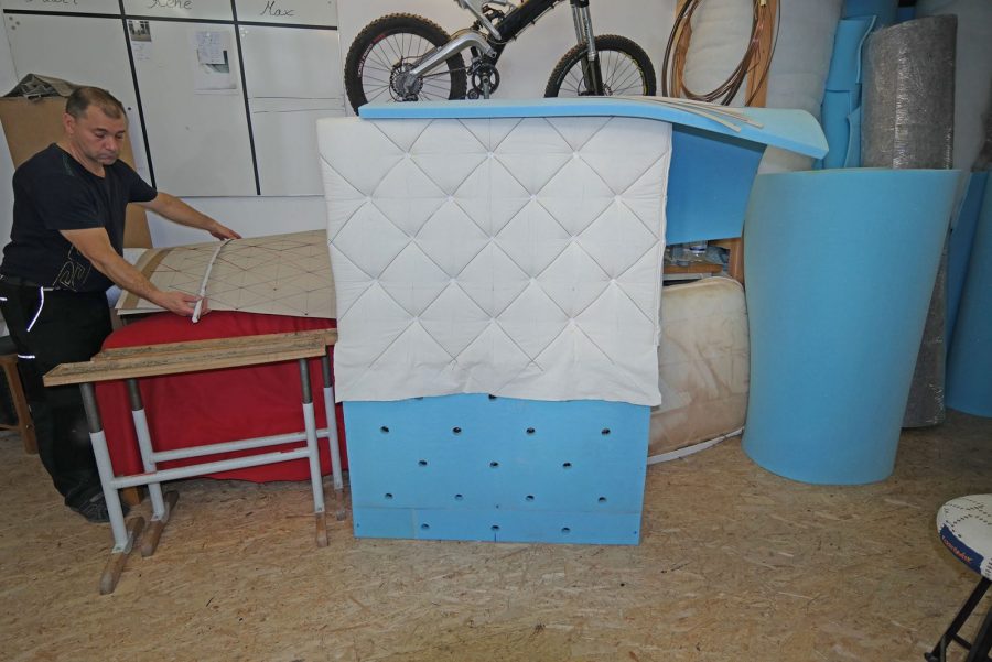 Metallbett, rot bezogen mit Rautenheftung